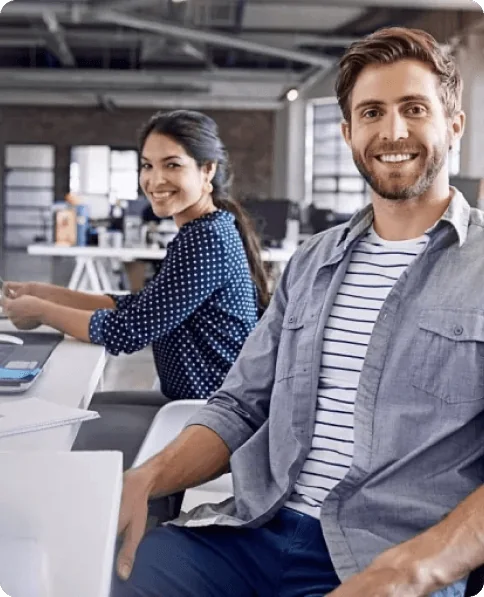 Colleagues smiling at their desks in the office